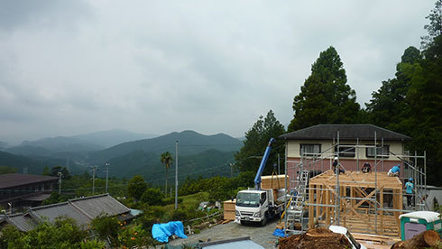 山々が連なる景色と木の家